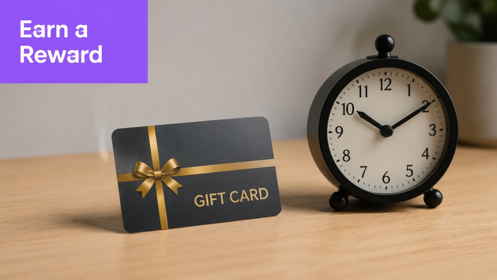 A black gift card with a gold bow next to a vintage alarm clock on a wooden desk.